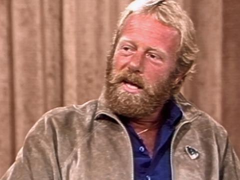 Head and shoulders shot of actor Jack Thompson on the set of The Mike Walsh Show. He is wearing a blue shirt and tan suede jacket. 