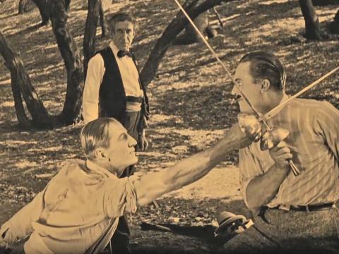Two men engaged in a fencing match in a still from the silent film Sword of Valor, 1924