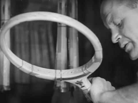 A man looks closely at a tennis racquet during its manufacture