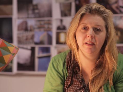Production designer Melinda Doring is interviewed with photographs in the background.
