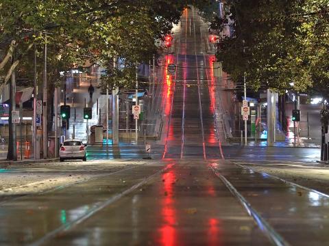 A wide shot of a completely empty main road in Melbourne at night time.