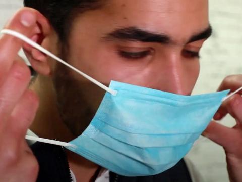 Close up of a man putting on a face mask.