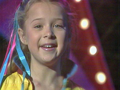 Close up of a young girl smiling at camera with colourful ribbons in her hair.