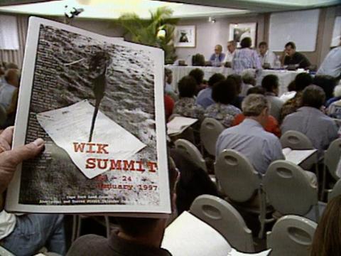  A meeting full of people, pamphlet in shot reading Wik Summit