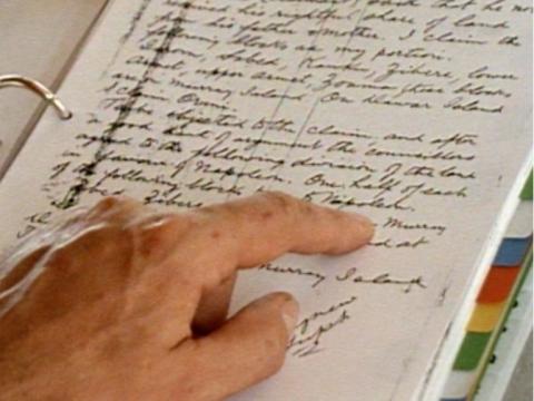 A hand pointing to an old transcript of a land dispute claim from the 1930s on Murray Island