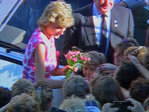 Princess Diana in 1988 holding a bouquet of flowers and greeting a crowd of people.