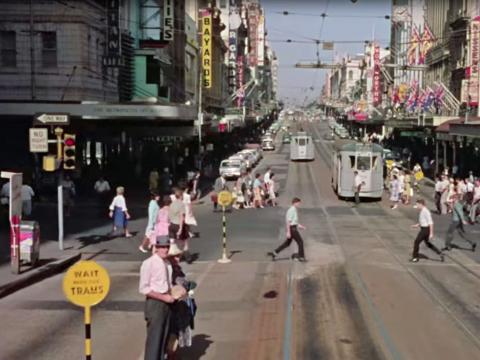 A busy cross-street in Brisbane in the 1960s. Trams, people, shops.