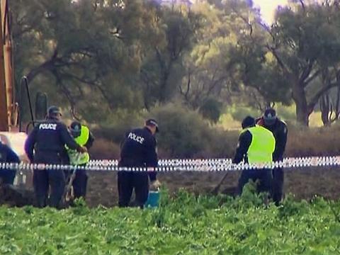 A group of police office in a taped off agricultural area in rural NSW search for remains of a body. Next to them is a large earth mover.