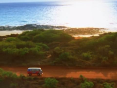A van driving along a dirt road close to the coastline