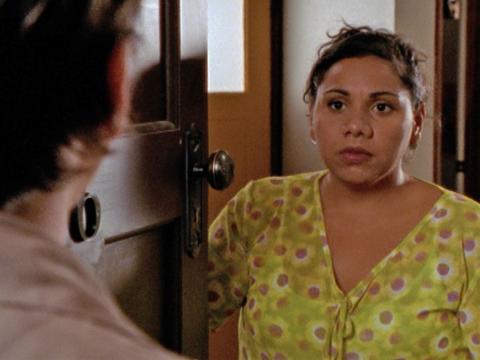A woman standing at an open door looking at a man on the other side.