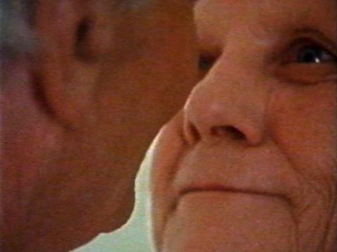 An older woman looking at an older man (seen from the back)