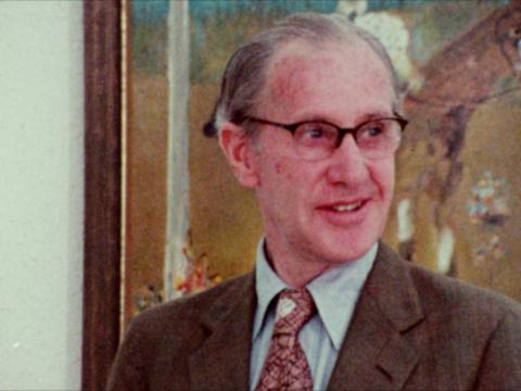 Artist Sidney Nolan smiling in front of one of his paintings in the Ned Kelly series.