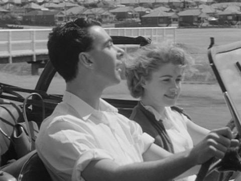A man and woman ride in an open top car