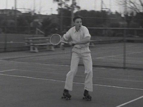 Young man playing tennis while wearing roller skates.