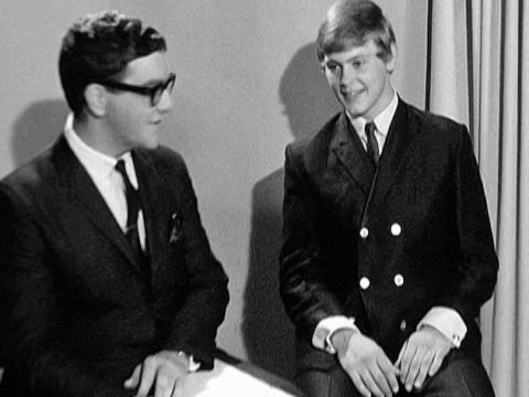 An 18 year old John Farnham sitting next to a reporter during an interview. 