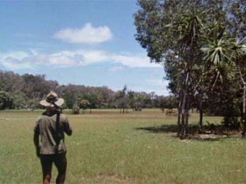 A wildlife ranger walks across an expanse of grass in the Northern Territory