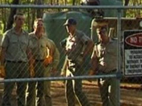 Security men behind a chain link fence