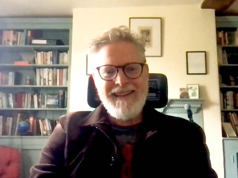 Tony McNamara being interviewed online from a study with two large bookcases