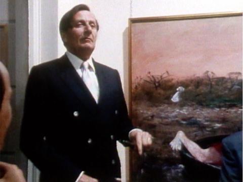 Barry Humphries standing in front of a painting
