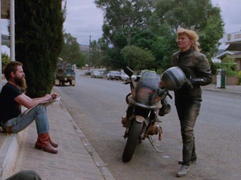 Deborra-lee Furness has dismounted her motorcycle outside a country pub in a still from the film Shame