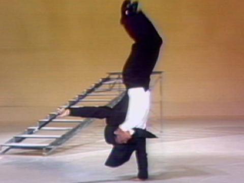 Acrobat Patrick Bradford performs a one-handed handstand.