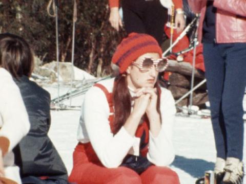 A yohng woman sits in the anow wearing very large sunglasses
