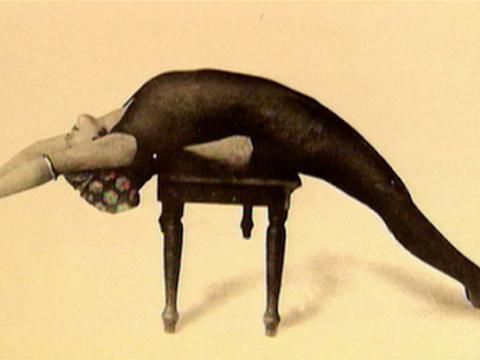 Annette Kellerman lying on her back across a small table with her arms and legs outstretched.