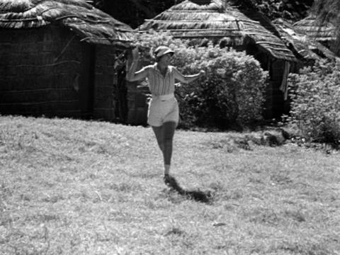 Annette Kellerman is running towards the camera across a patch of grass.