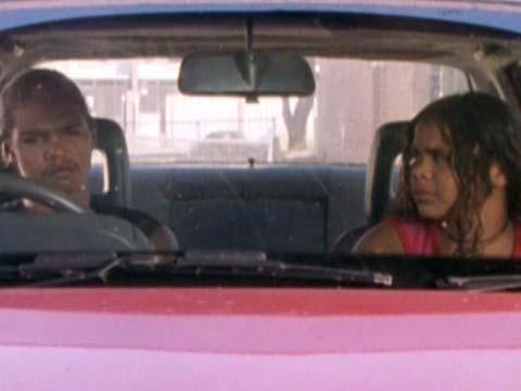 A young man and woman seated in a car, talking