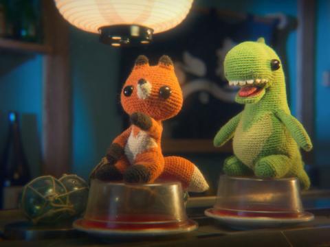 Animation still of a knitted dinosaur and a knitted fox
