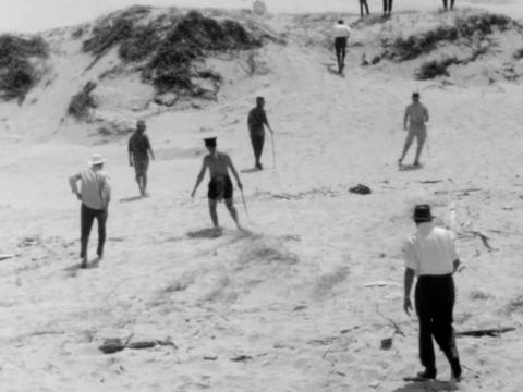 Male figures walking in sand dunes