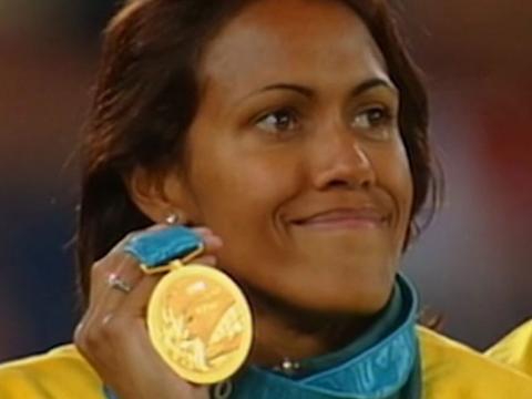 Athlete Cathy Freeman smiles as she holds up her gold medal.