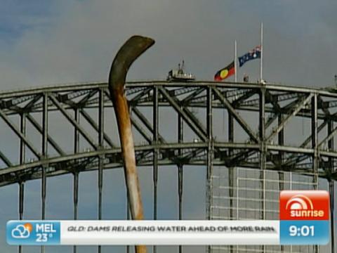The Sydney Harbour Bridge has two flags flying at half mast. One is the Australian Aboriginal flag and the other is the Australian flag.