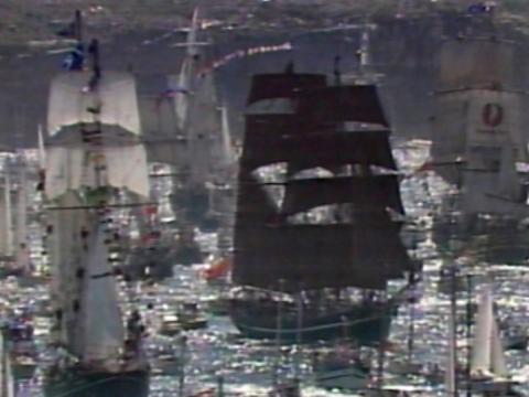 Tall ships and smaller watercraft crowd in together on a shimmering Sydney Harbour on Australia Day, 1988.