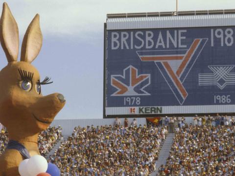 Matilda, the huge kangaroo mascot of the 1982 Brisbane Commonwealth Games, looks out over the crowd. There is a digital sign next to her that says Brisbane 1982.