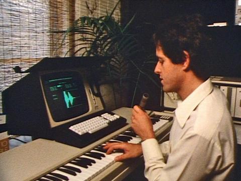 Inventor Peter Vogel pressing keys on his invention, The Fairlight CMI. It also shows a 1980s computer monitor and keyboard.