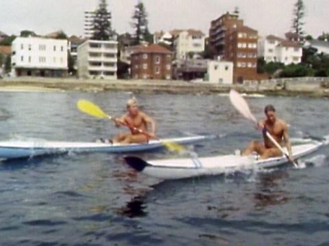 Two men in kayaks paddling in the water.