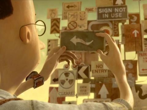 Animaton still of the rear view of a boy examining a card that has a wavy arrow on it.