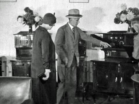 A middle-aged man and wife looking at a gramophone, circa 1925.