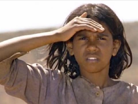 Young Indigenous girl shielding her eyes from the sun.