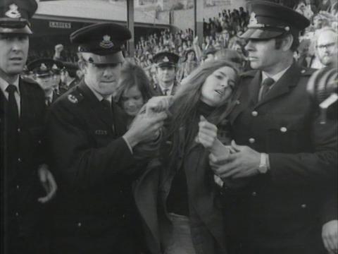 A protesting woman is escorted away by police