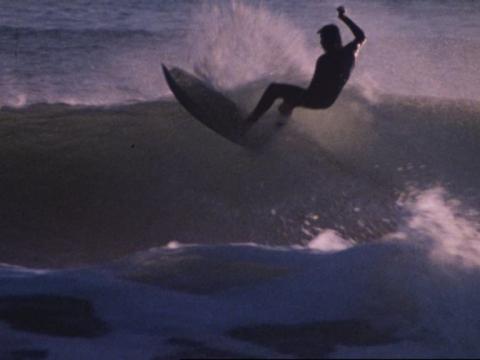 A surfer is silhouetted against a wave