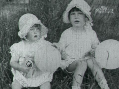 Two young children hold balloons