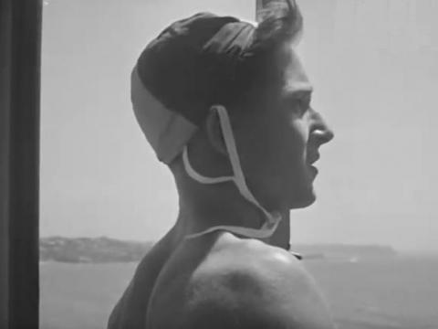 Black and white image of a young surf lifesaver on the lookout for danger, circa 1940s
