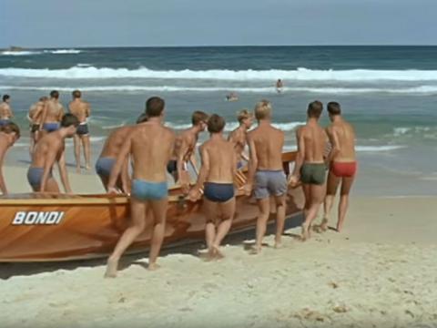 Surf lifesavers at Bondi beach pushing a rowboat into the water