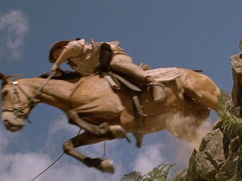 A rider and horse leap off a cliff