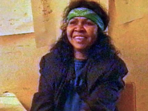Musician and songwriter Ruby Hunter pictured from the waist up, smiling during an interview. She is wearing a navy blue jacket and green bandanna.