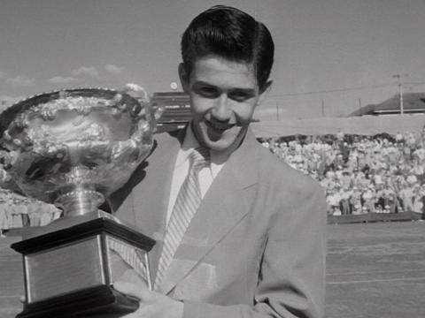 Ken Rosewall holds a tennis trophy.