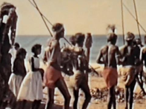 Aboriginal men with spears performing a ceremony by the sea