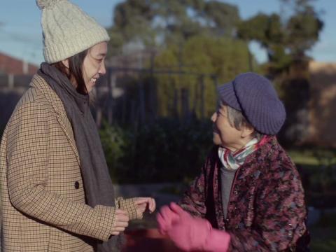 A young Chinese woman with an older Chinese woman in backyard garden